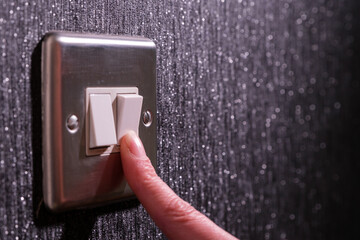finger turning off light switch with copy space - obrazy, fototapety, plakaty