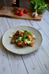 Rice with lamb meat and vegetables on a plate on a wooden table