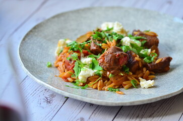 Rice with lamb meat and vegetables on a plate on a wooden table