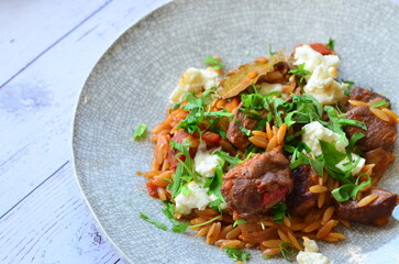 Rice with lamb meat and vegetables on a plate on a wooden table
