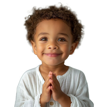 A young child with brown hair and a white shirt is smiling and praying