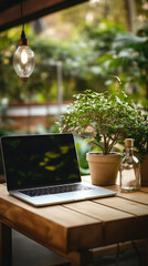 Laptop on a wooden table in a cafe with green plants .