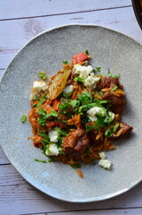 Rice with lamb meat and vegetables on a plate on a wooden table