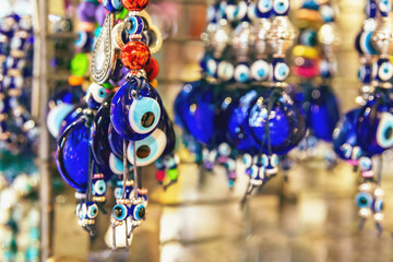 Evil eye amulets in a deep cobalt blue, symbolizing protection, dangle amongst trinkets in a Turkish market. Istanbul, Turkey (Turkiye)