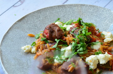 lamb stewed with tomatoes and orzo, background of greek traditional food youvetsi