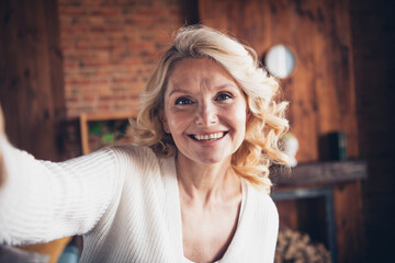 Photo portrait of lovely retired woman take selfie toothy smile wear casual clothes cozy home interior living room in brown warm color