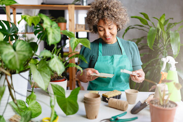 A mature woman of mixed race working in a home garden, choosing seeds for spring seed starting