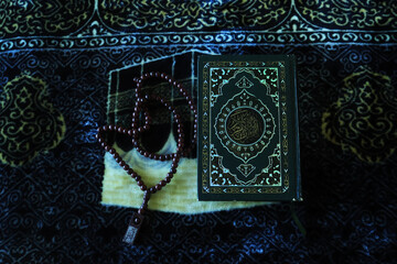 The holy book Al Quran for Muslims. Al-Quran on a prayer mat and prayer beads