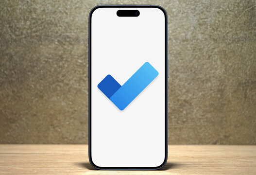 Microsoft To Do logo is displayed on a modern smartphone standing on a wooden desk, cloud-based task management application, Microsoft, organization