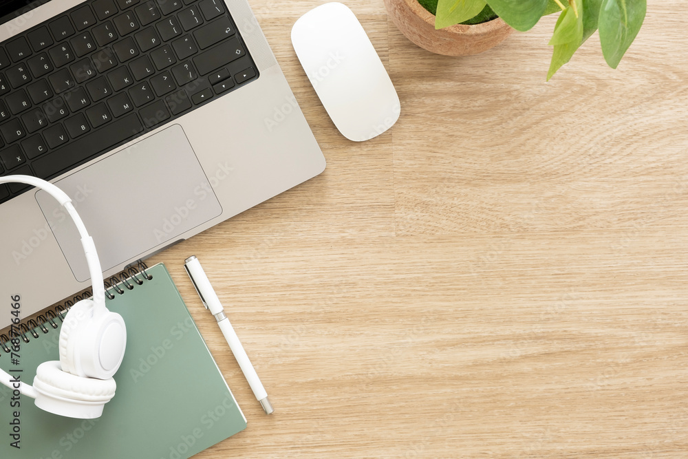 Poster simple workplace with laptop, notepad and headphone on wooden table with copy space for text.
