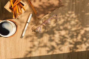 Top view glasses, coffee cup and notebook on wooden table. Copy space for your text.