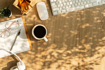A cup of coffee, notebook, glasses and headphone on wooden table. Top view with copy space.