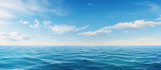 Obraz premium A serene blue ocean under the clouds, with gentle waves on the water surface and a clear horizon against the sky