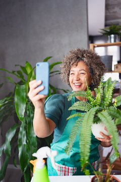 Mature smiling woman gardener taking a selfie photo in her home garden