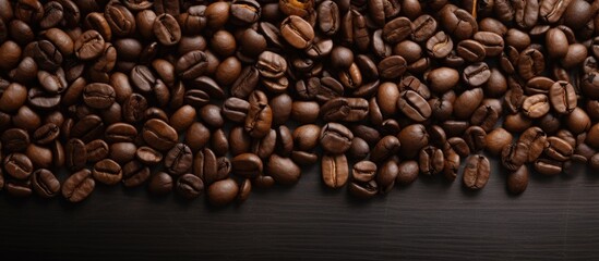Fototapeta premium Scattered roasted brown coffee beans arranged on a black background creating a textured and rich coffee bean display