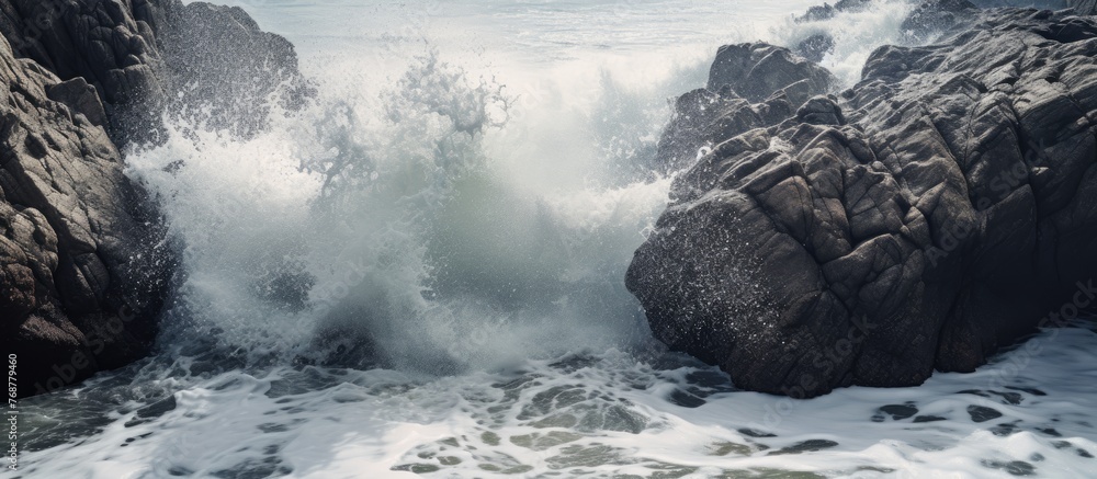 Poster Powerful ocean waves relentlessly crash into the sturdy rocks on the shore, creating a mesmerizing display of nature's force
