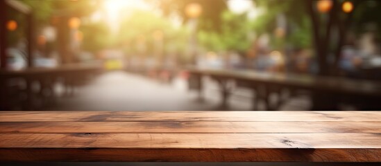 A wooden table top is shown with a blurred cityscape in the background, creating a versatile setting for product display or montage - obrazy, fototapety, plakaty