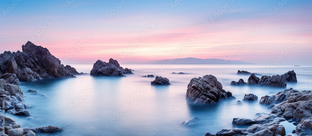 Poster a serene tropical rocky beach at sunrise captured with a long exposure technique, creating a soft an