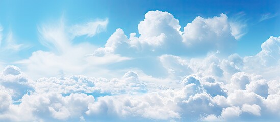 Fluffy white cumulus clouds float peacefully in the vast expanse of the clear blue sky above
