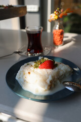 Ramadan Dessert Gullac Close-Up Shot on Table with turkish tea
This captivating close-up shot showcases a delectable serving of Gullac, a traditional Turkish dessert typically enjoyed during Ramadan. 