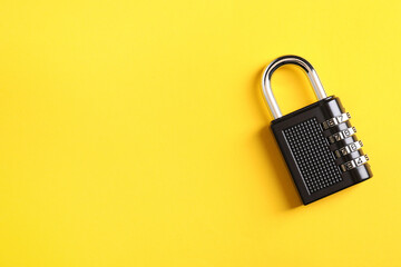 Steel combination padlock on yellow background, top view. Space for text