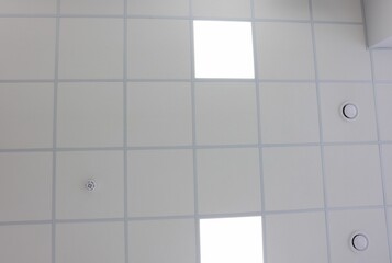 White ceiling with PVC tiles and lighting indoors, bottom view