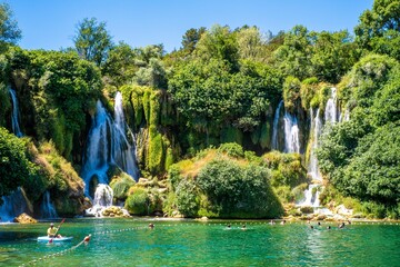 Majestic Kravica Waterfall cascading down amidst lush greenery and trees in Bosnia and Herzegovina © Wirestock