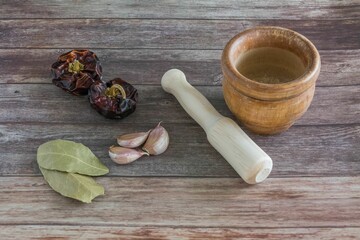 mortar and pestle with herbs on wooden surface.