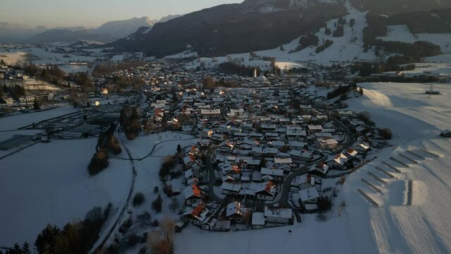 Drone footage over town of Nesselwang in Bavaria, Germany with snowy hills and mountains