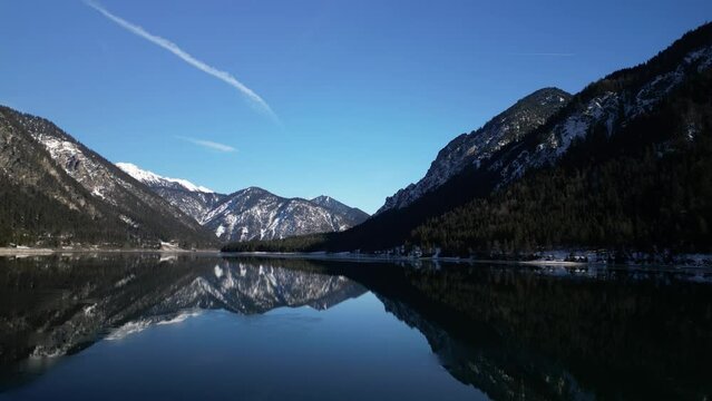 Beautiful scene of reflecting mountains with top snow on plansee lake in Reutte Town in Austria