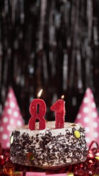 Number eighty-one birthday candle on sweet cake on dark background, 81st birthday. Blow out the holiday candle.