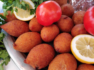 Traditional Turkish fried bulgur cutlets stuffed with minced meat, on a plate with lemon