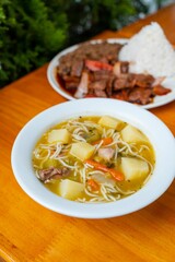 two bowls of soup and a plate with rice on a table