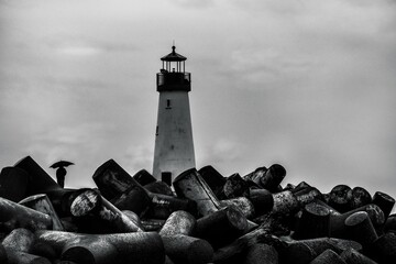 a black and white photo of some rocks and a lighthouse