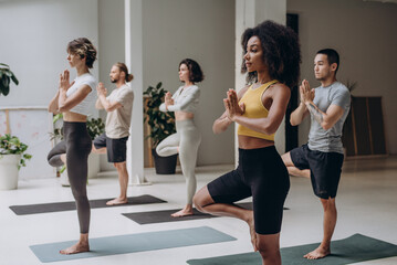 Five diverse people participating in yoga session indoors - 768799087