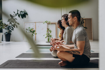Motivated group of five people practicing yoga in studio - 768799233