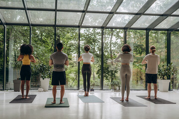 Sports team standing on yoga mats during training in studio