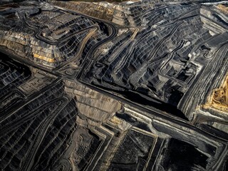 a massive dirt pit with lots of coal on it and two other smaller piles