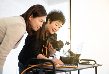 스튜디오에서 사진을 촬영하며 고객과 소통중인 중장년의 여성 사진작가