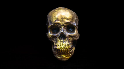 Human skull gold on wood table dark background