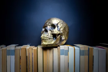 Poster Human Skull gold on books dark background © antoniofrancois