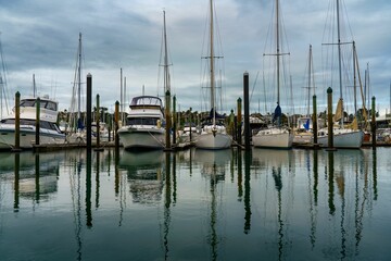 Fleet of vessels moored at a harbor or coastal dock, with the sun glinting off their decks