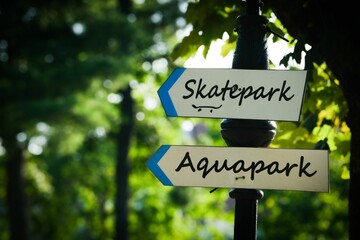 Closeup shot of a pole with a skatepark and an aquapark sign