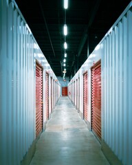 Interior hallway of a storage building with red shuttered doors and brick columns along the walls