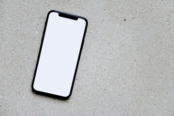 Mobile phone with blank screen on grey concrete background, top view, mock up