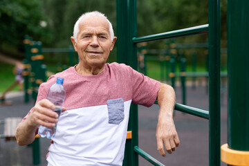 Mature man quenches her thirst from bottle after jogging in park