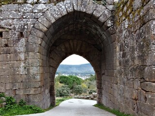 Stunning view of a valley through an aged, stone-built arch. Galicia, Spain.