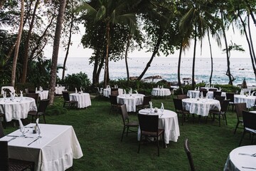 Stunning outdoor wedding setting with white tables and chairs arranged on a beach