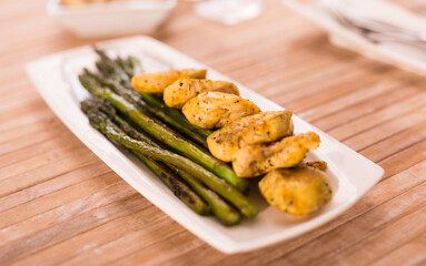 Cooked dish. Chicken nuggets with green asparagus on plate