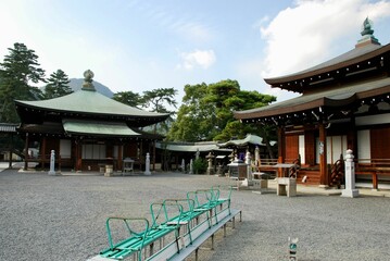 a bench that is sitting outside by some buildings with roof